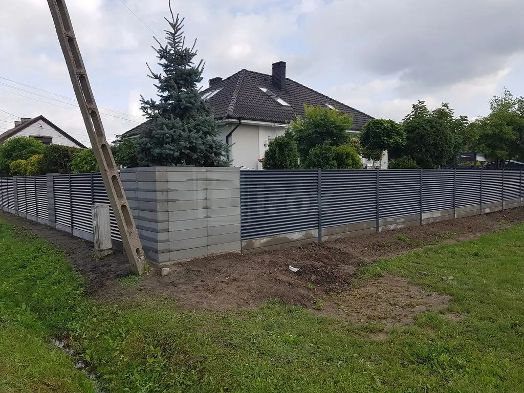 Ogrodzenie żaluzjowe z podmurówką w pobliżu betonowego słupa energetycznego